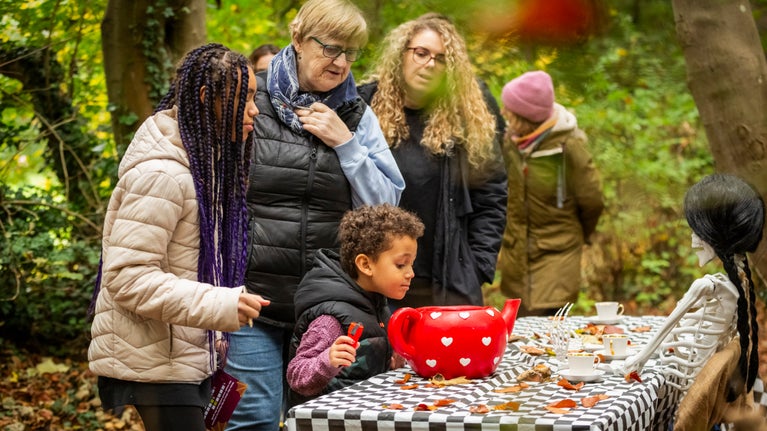 A family look into a teapot on a woodland Halloween trail